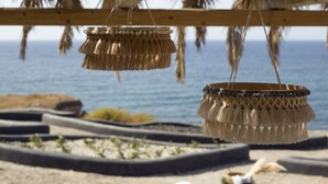 Een strandsetting met een rieten constructie, hangende decoraties en uitzicht op zee.