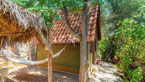 A rustic wooden building with a tiled roof, surrounded by trees and a hammock. - Olympos Mocamp Kas (Kas)
