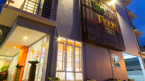 A multi-story hotel with a prominent sign reading "The Room" and balconies on each floor. - The Room (Udon Thani)