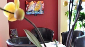 Une pièce avec un mur d’accent rouge, un tableau, un téléviseur et une table avec des chaises.