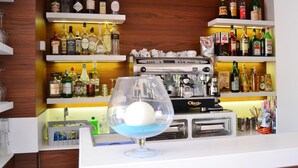 Un espace bar avec des étagères remplies de bouteilles d’alcool, une machine à café et un verre contenant une sphère bleue.