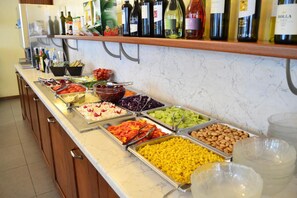 A buffet with various food options and a selection of wine bottles on the counter.