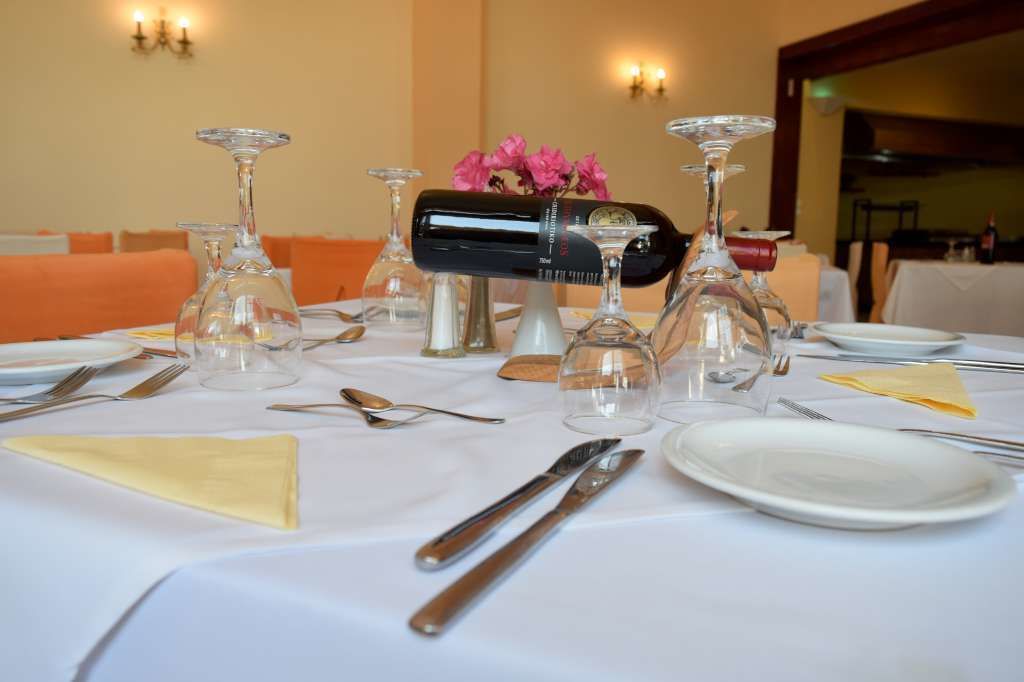 A dining table set with wine glasses, a bottle of wine, and a vase with flowers.