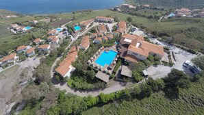 An aerial view of a coastal resort with multiple villas, a central pool area, and a view of the sea. - Belvedere Aeolis Hotel (Lesvos)