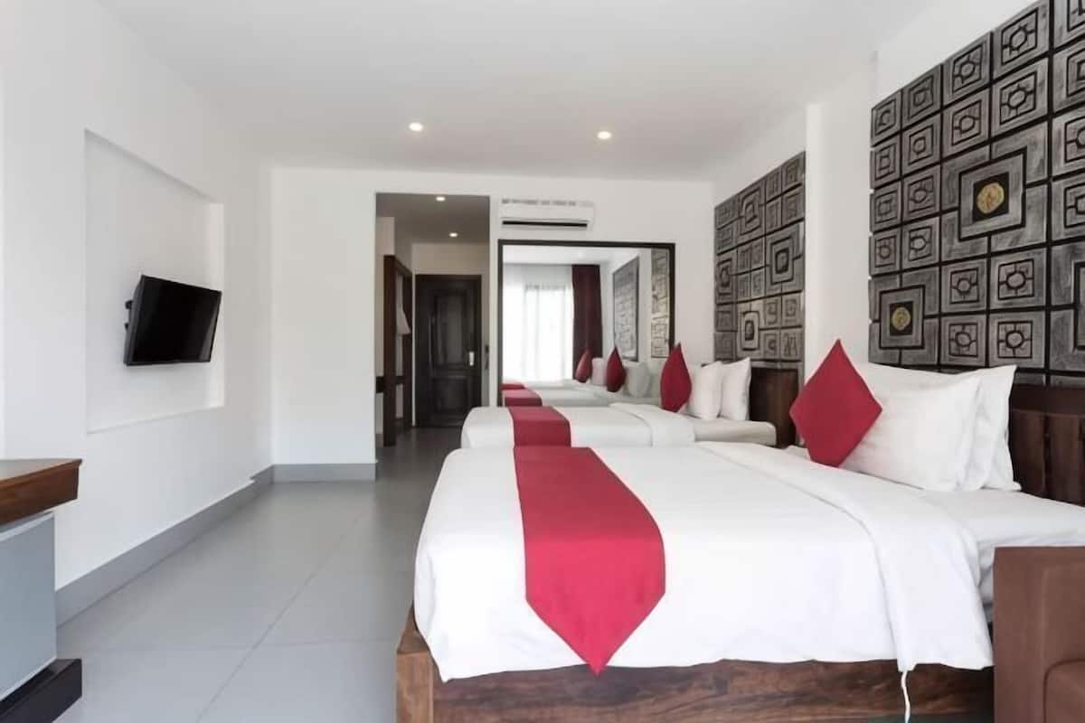 Habitación de hotel con una cama grande, un televisor y un papel tapiz estampado.