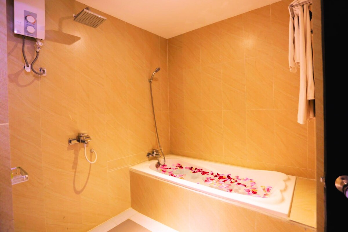 A bathroom with a bathtub, shower, and towel rack.