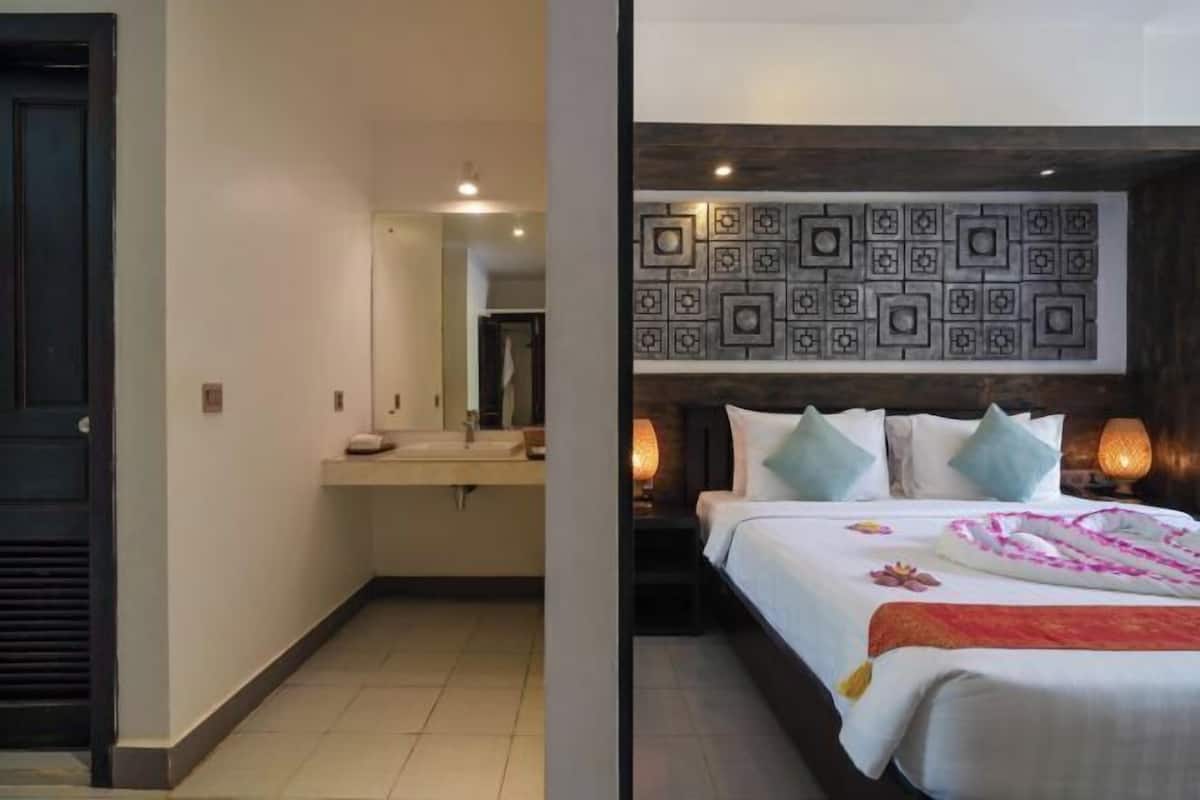 Habitación de hotel con cama, lámparas de noche, un espejo y una pared con diseño geométrico.