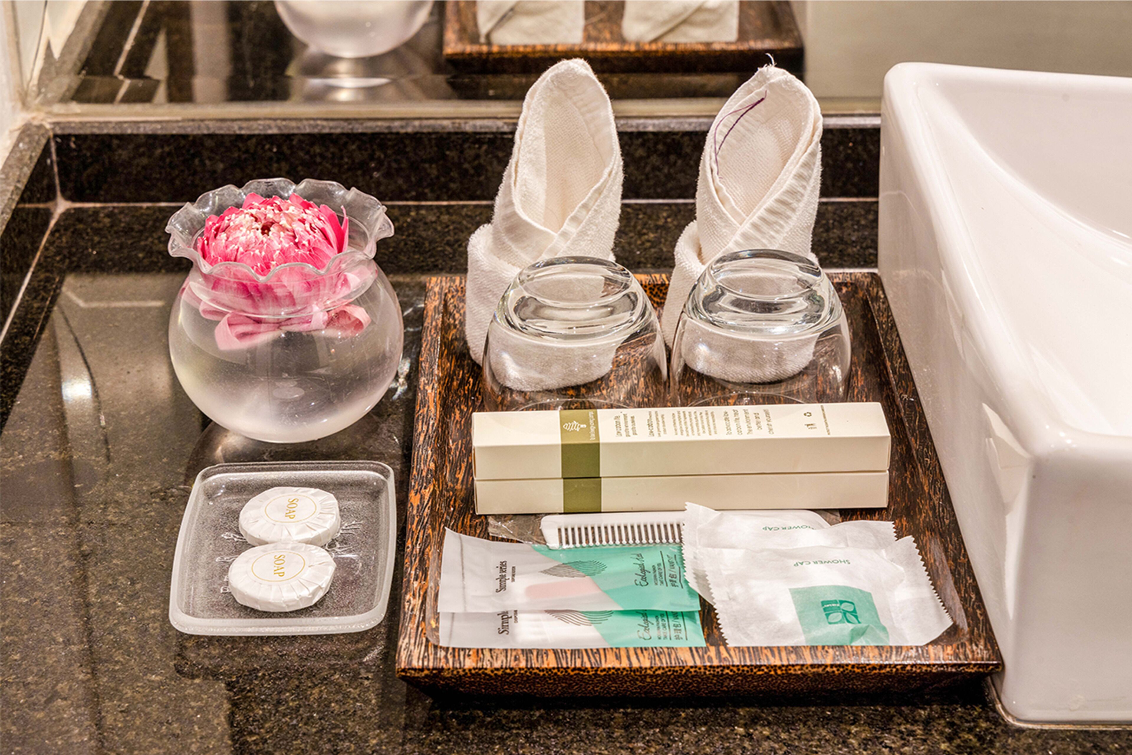 A tray with toiletries including a flower, slippers, and packaged items.
