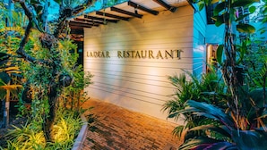 A restaurant entrance with a sign reading "LADEAR RESTAURANT" surrounded by lush greenery and a brick pathway. - Ladear Privilege Rooms (Siem Reap)