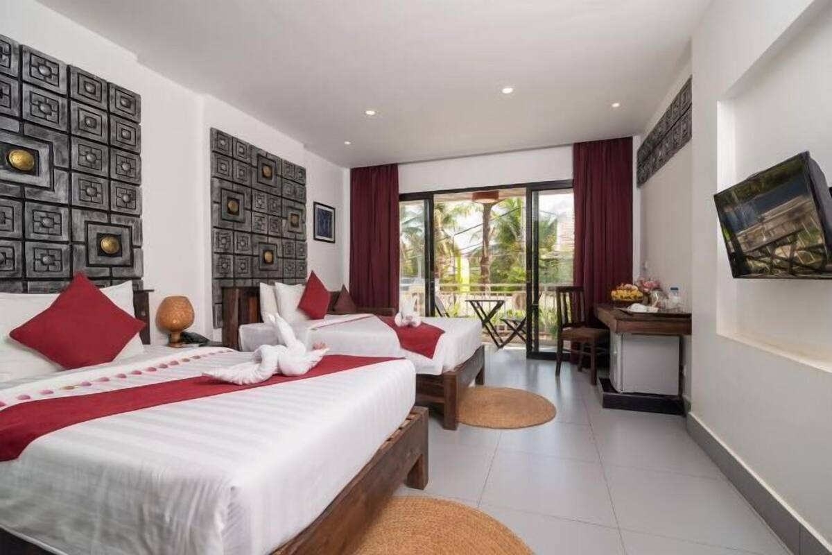 Ein Hotelzimmer mit zwei Betten, einem Schreibtisch, einem Stuhl, einem Balkon mit Blick und dekorativen Wandpaneelen.