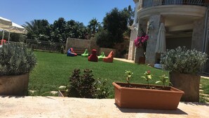 A courtyard with a well-maintained lawn, colorful bean bags, and potted plants. - Hotel Marsala (Kas)