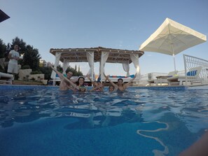 Una piscina con un pabellón, sillas de descanso y una sombrilla.