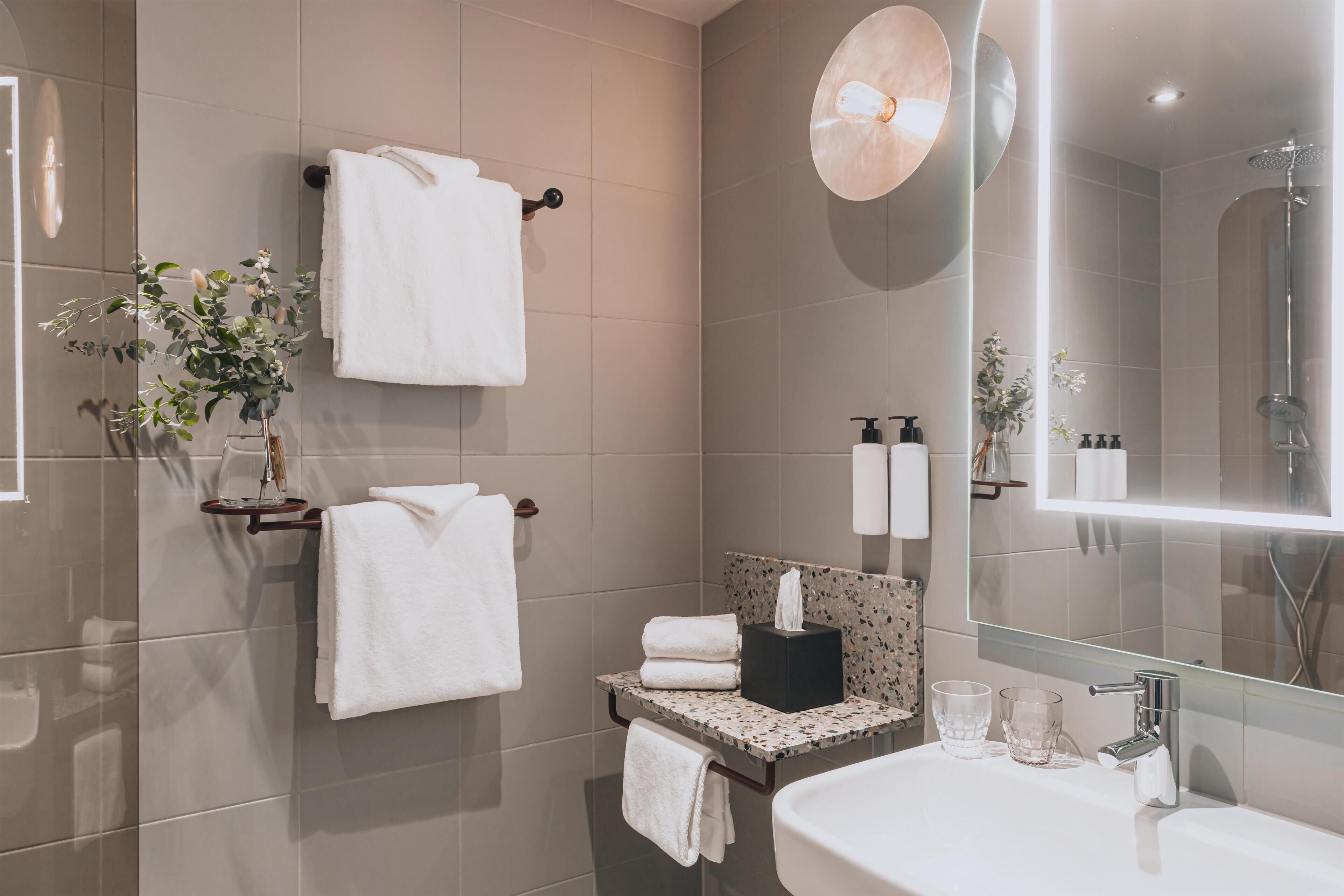 Un baño moderno con un espejo grande, un lavabo y un perchero para toallas.
