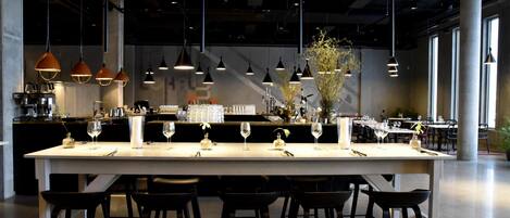 A modern bar area with a long counter, multiple hanging pendant lights, and bar stools.