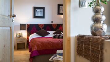 A bedroom with a bed, a nightstand, a lamp, and a wall-mounted light switch.
