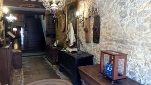 Un intérieur rustique avec des murs en pierre, un banc en bois, une statue et une lampe de style vintage.