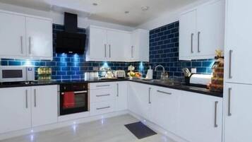 A modern kitchen with white cabinets, a black countertop, and blue-tiled backsplash.