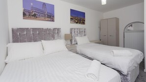 Een hotelkamer met twee bedden, een kledingkast en twee stadsgezichten in lijsten aan de muur.