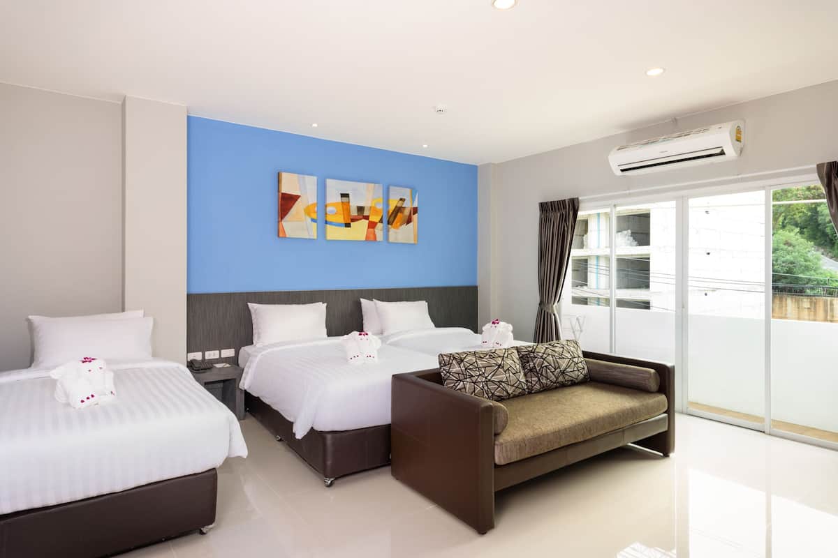 Habitación de hotel con dos camas, un sofá y un ventanal grande.