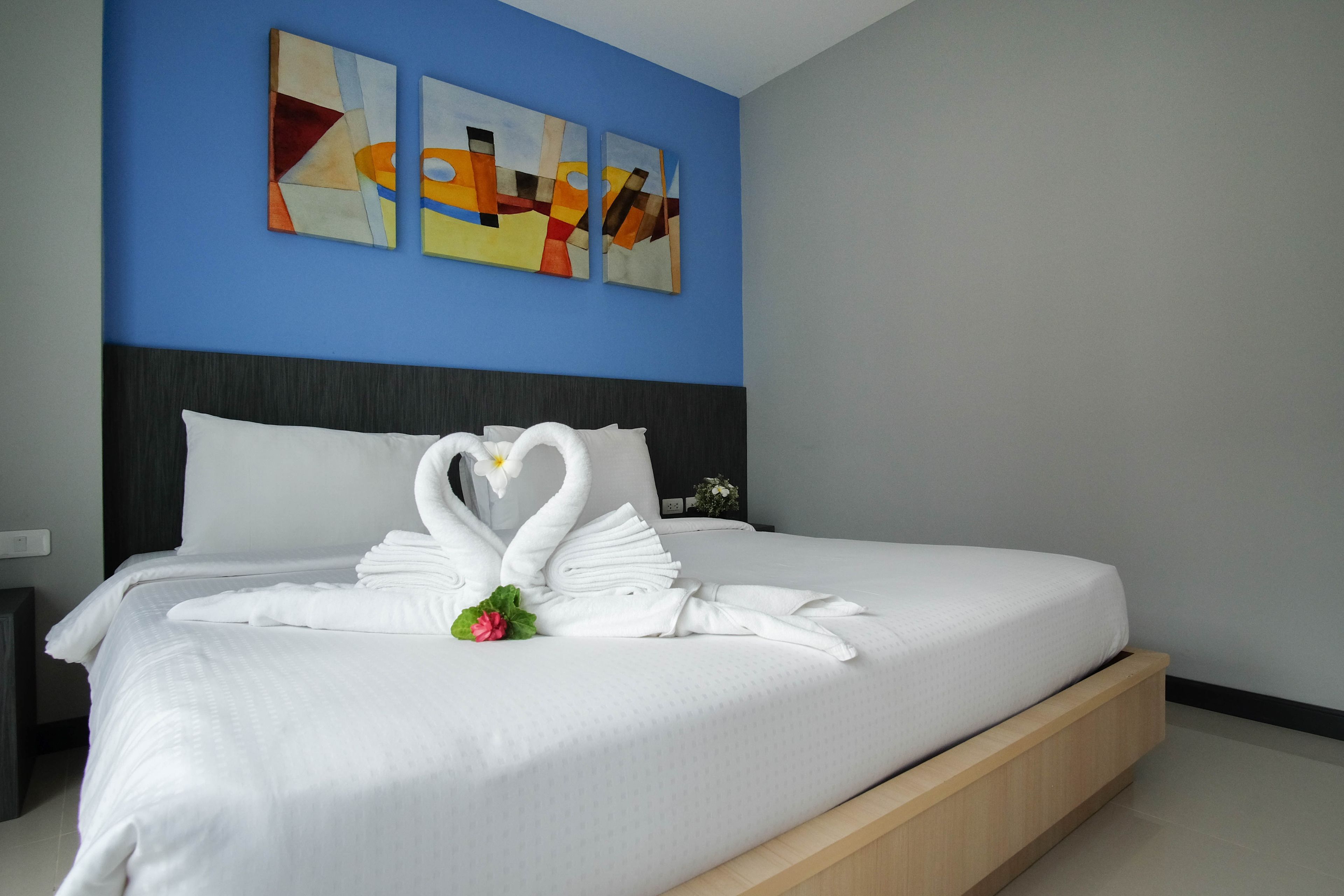A neatly made bed with white linens and a decorative swan towel arrangement.