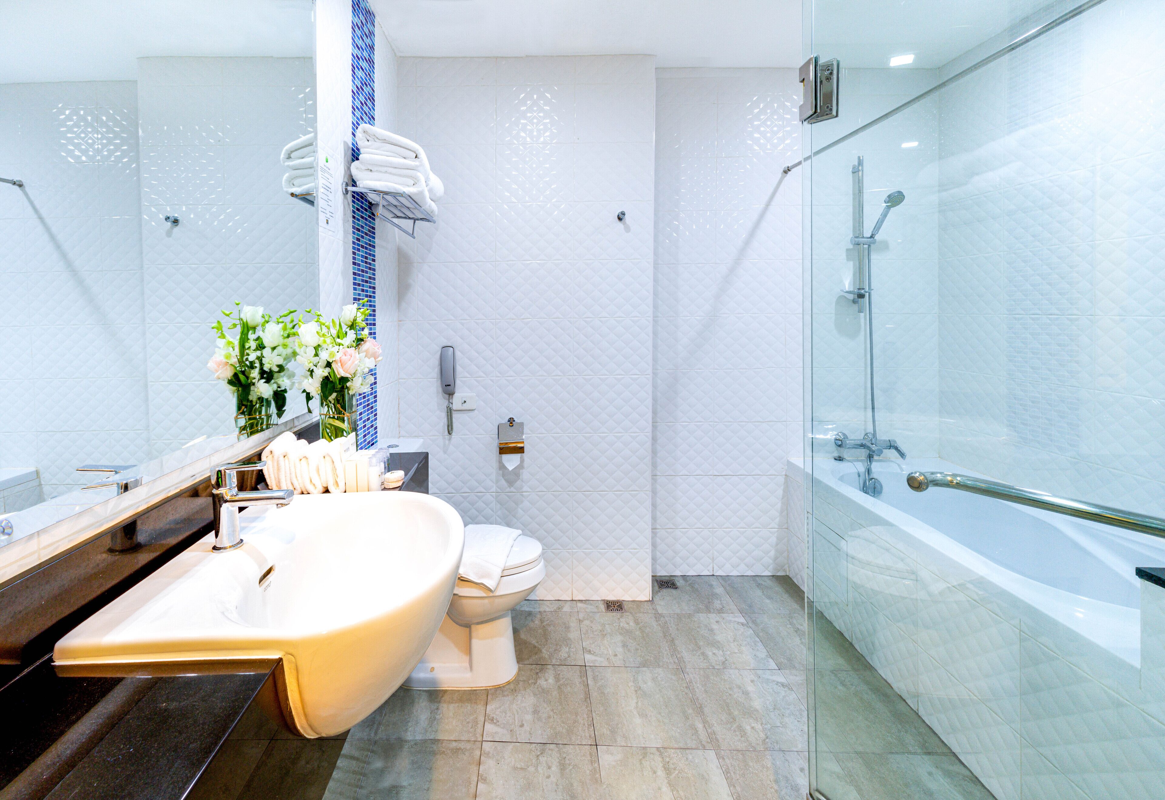 Ein modernes Badezimmer mit freistehender Badewanne, einem geräumigen Waschtisch mit Waschbecken, einer Toilette und einer Duschkabine.