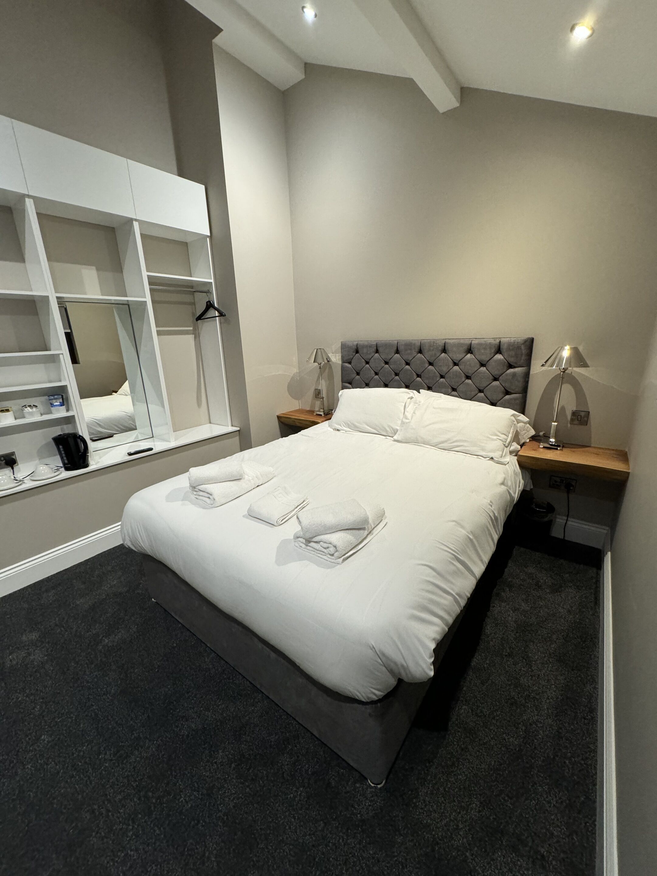 Un dormitorio moderno con cama, mesitas de noche, un armario y un espejo.