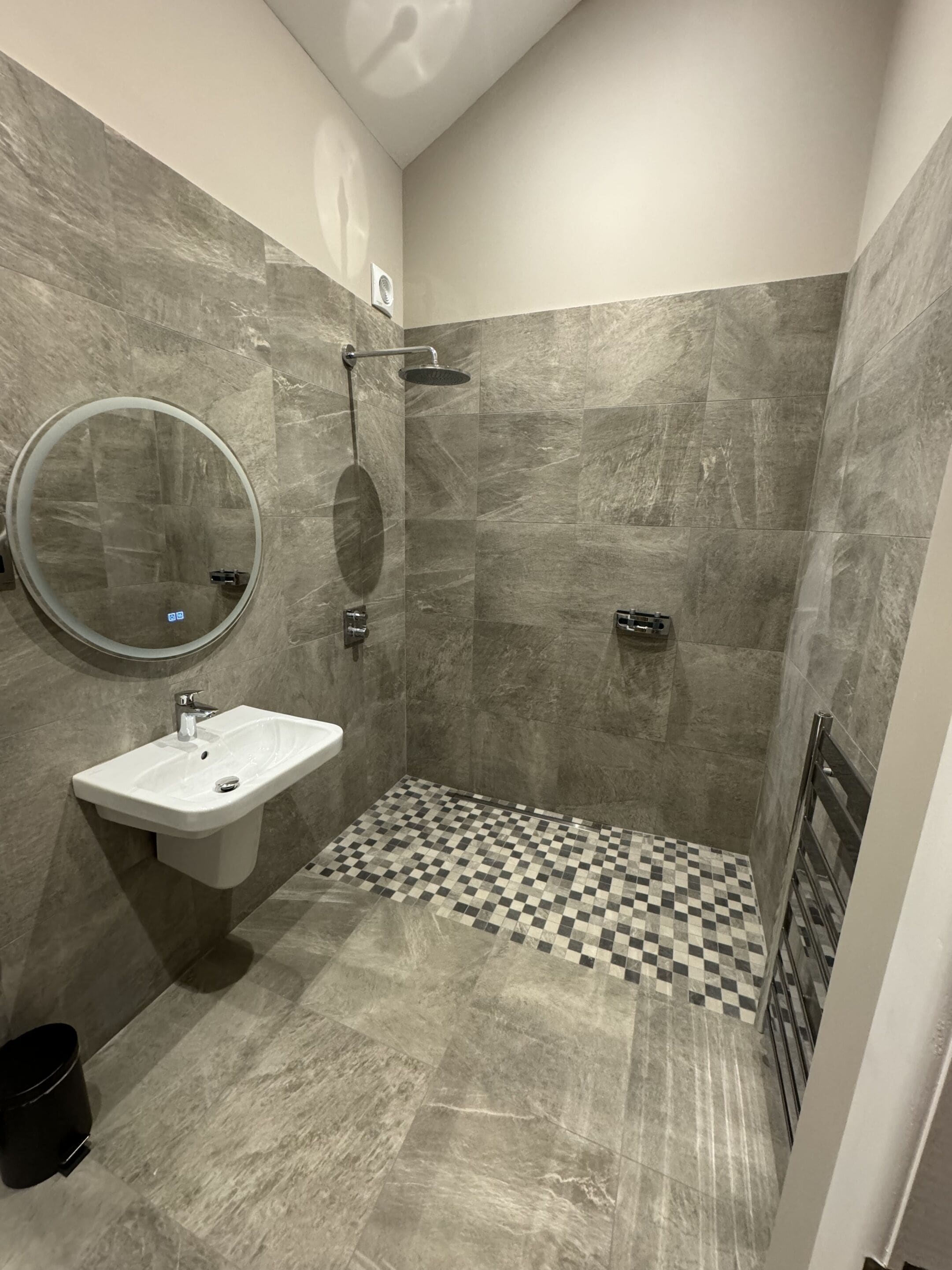 A modern bathroom with a shower, a sink, and a mirror.