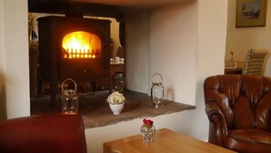 A cozy living room with a wood-burning stove, leather armchair, wooden coffee table, and decorative items. - The 3 Millstones Inn (Clitheroe)