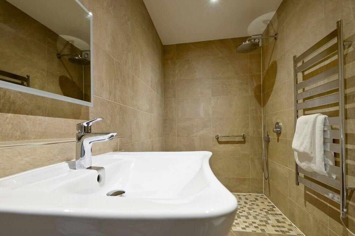 A bathroom with a white sink, a shower, and a towel rack.