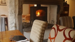 A cozy room with a fireplace, a dining table set with plates and cutlery, and a patterned armchair. - The 3 Millstones Inn (Clitheroe)