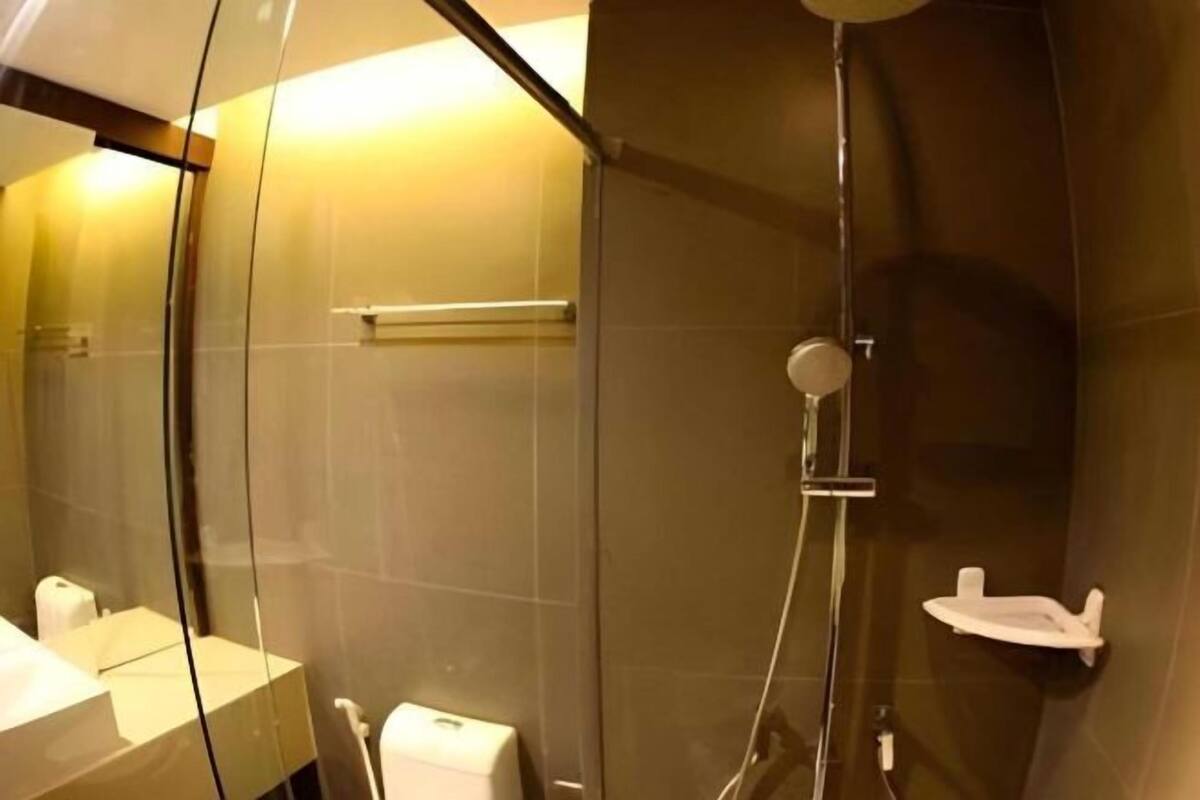 Moderni kylpyhuone, jossa on lasiseinä, suihku, wc ja pesuallas.