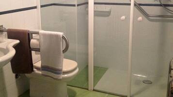 A bathroom with a sink, toilet, and glass shower enclosure.