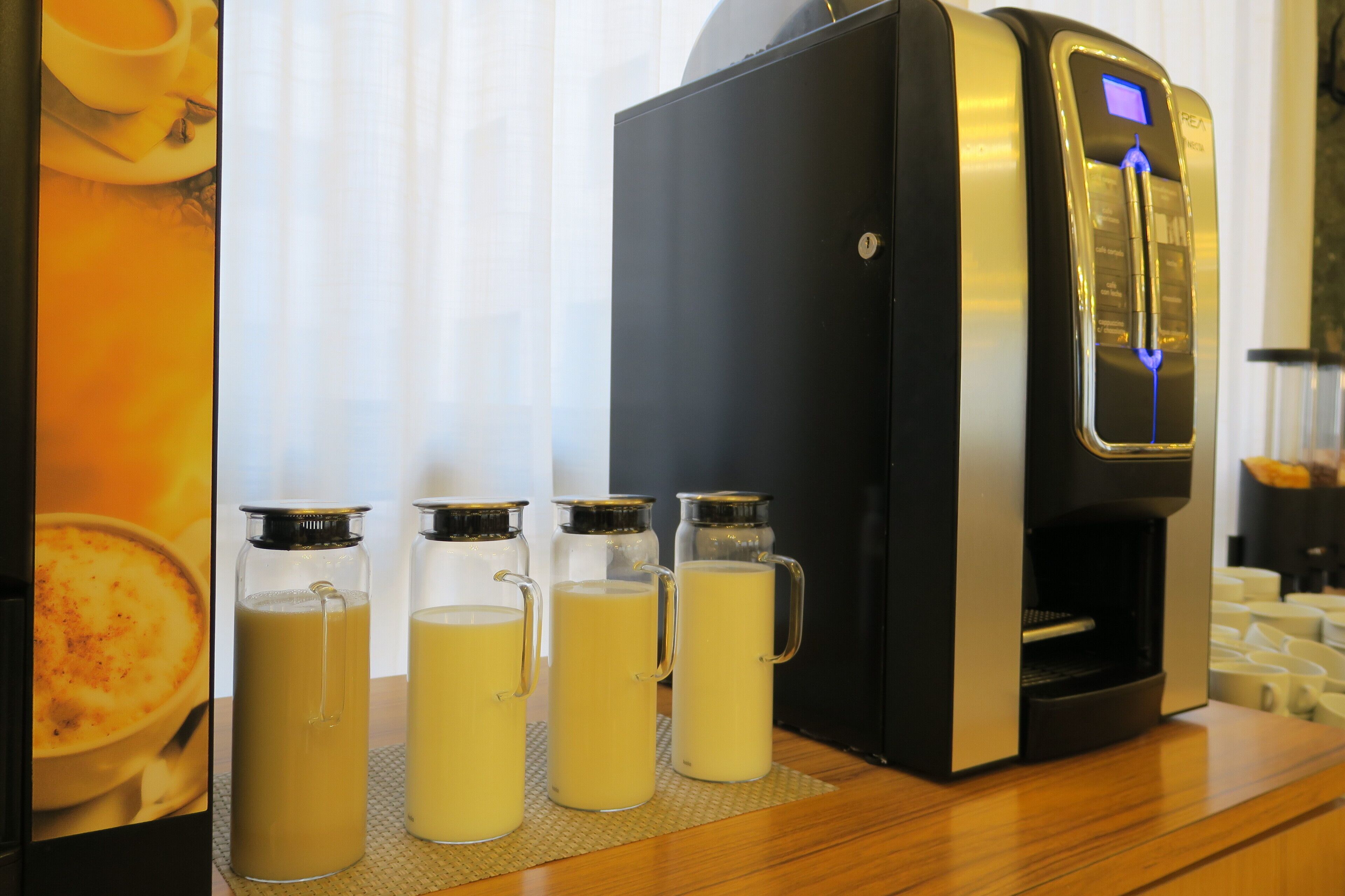 A coffee machine with four glass carafes of coffee on a wooden counter.