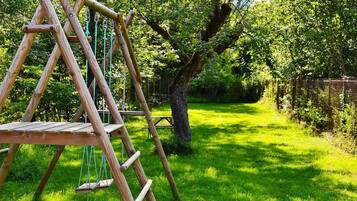 Relax in a serene garden setting with a charming swing set and lush greenery.