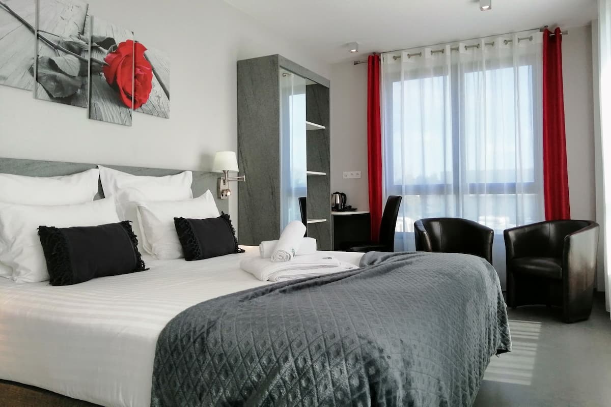 A modern hotel room with a large bed, a desk, and a chair.