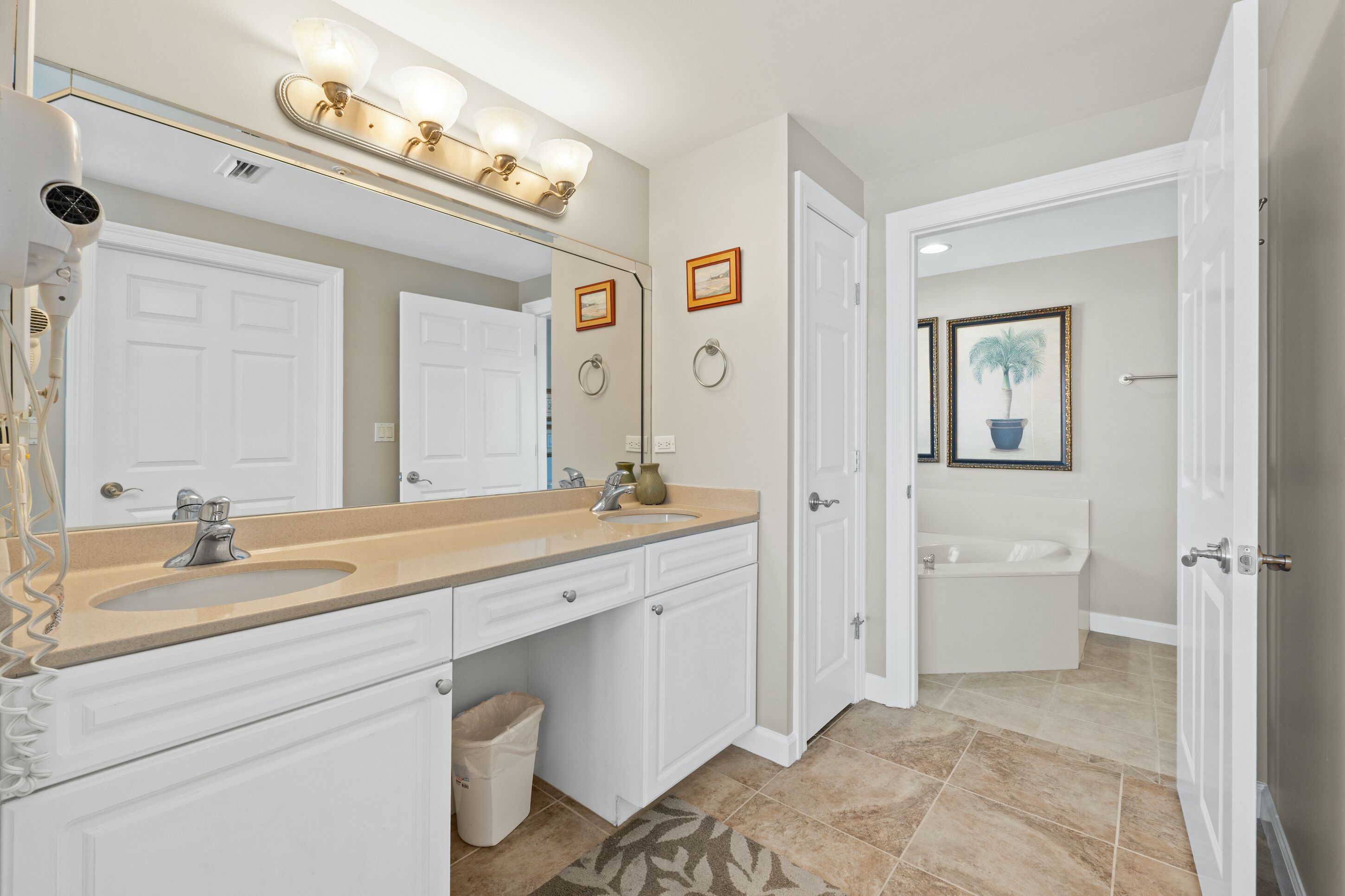 A bathroom with a double sink vanity, a large mirror, and a bathtub.