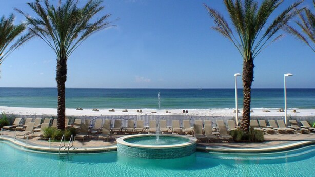 A pool area with a view of the beach and ocean.