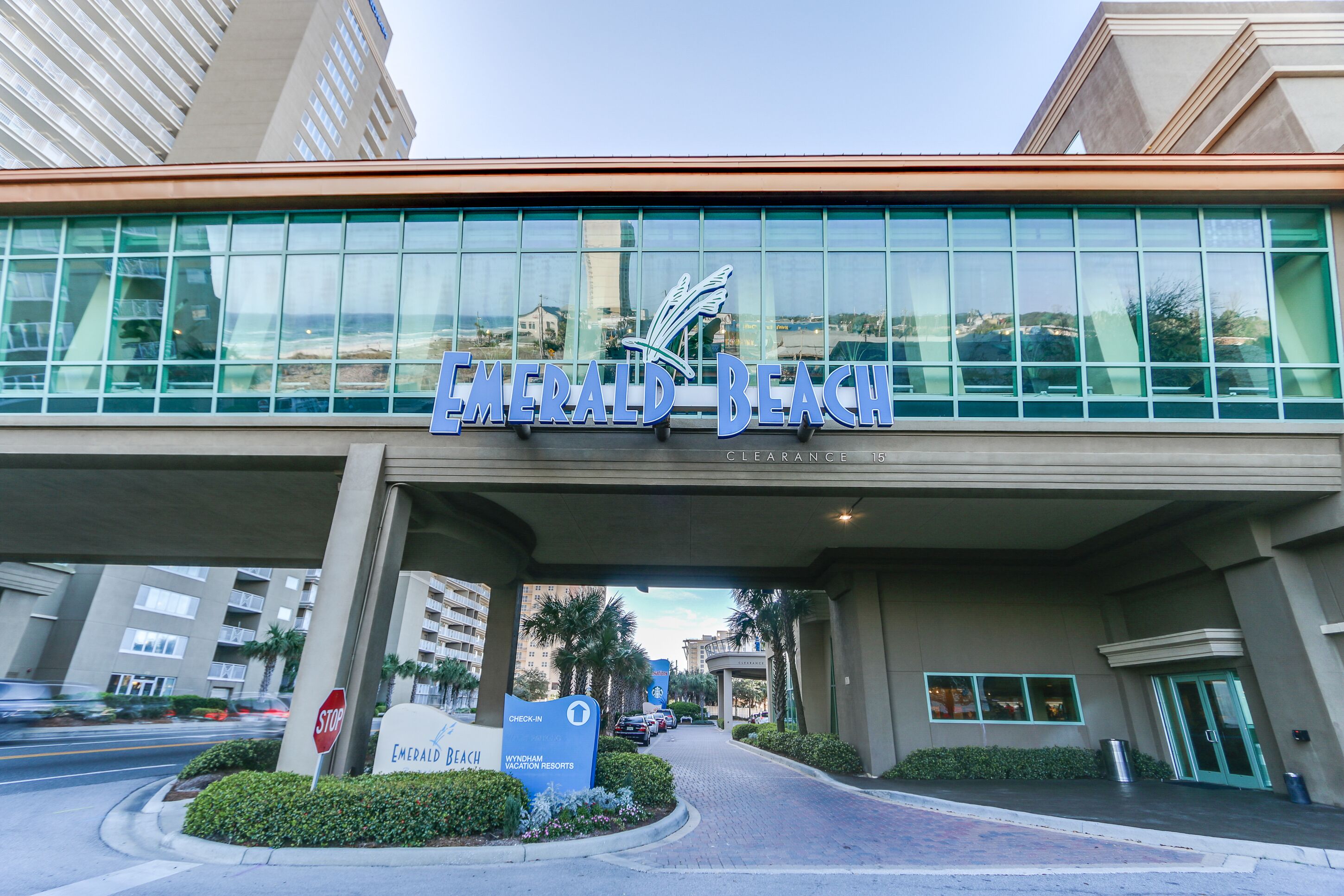 A hotel entrance with a large sign reading "Emerald Beach" and a "Check-in" sign.