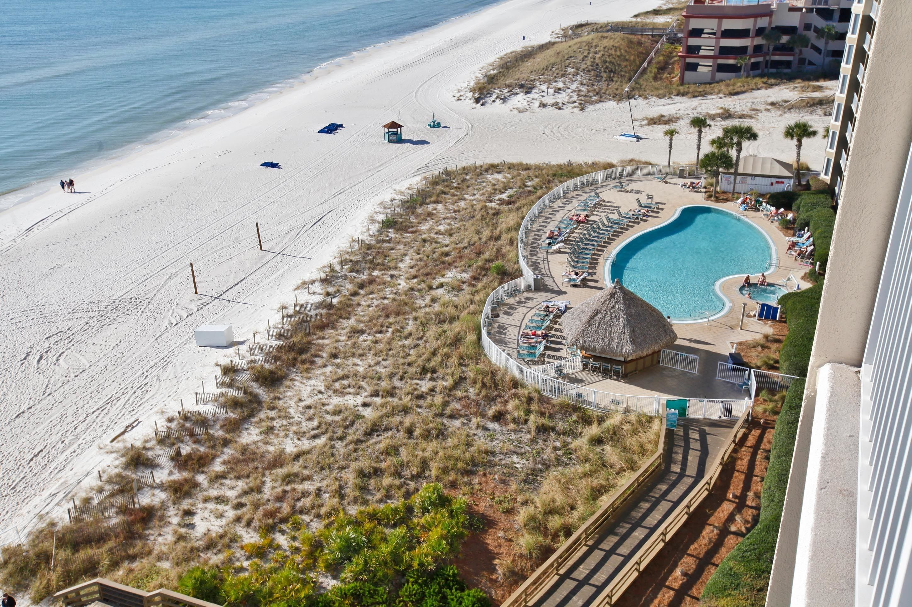 A beach resort with a swimming pool, beach chairs, and a thatched-roof hut.