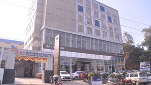 Un hotel con fachada moderna, amplias ventanas y un letrero que dice 'SAI RESIDENCY'.