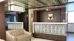 Un área de recepción con un separador decorativo, una mesa de recepción, un sofá y un equipo de aire acondicionado.
