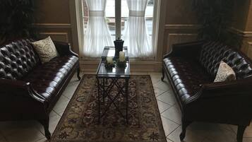 Um quarto com dois sofás de couro, uma mesa central com velas e um tapete estampado.