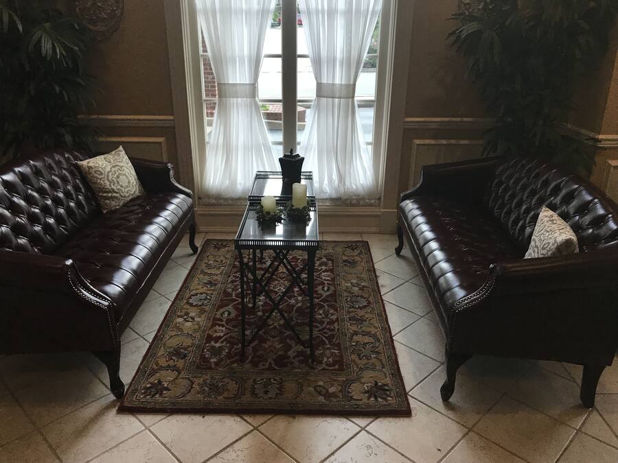 Um quarto com dois sofás de couro, uma mesa central com velas e um tapete estampado.