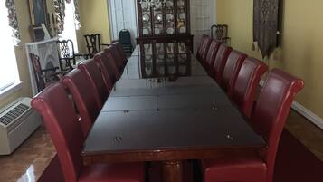 Una larga mesa de comedor con sillas tapizadas rojas, un candelabro y un aparador grande con puertas de cristal.