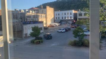 A parking lot with several cars, a building with a 'NO PARKING' sign, and a hill in the background.