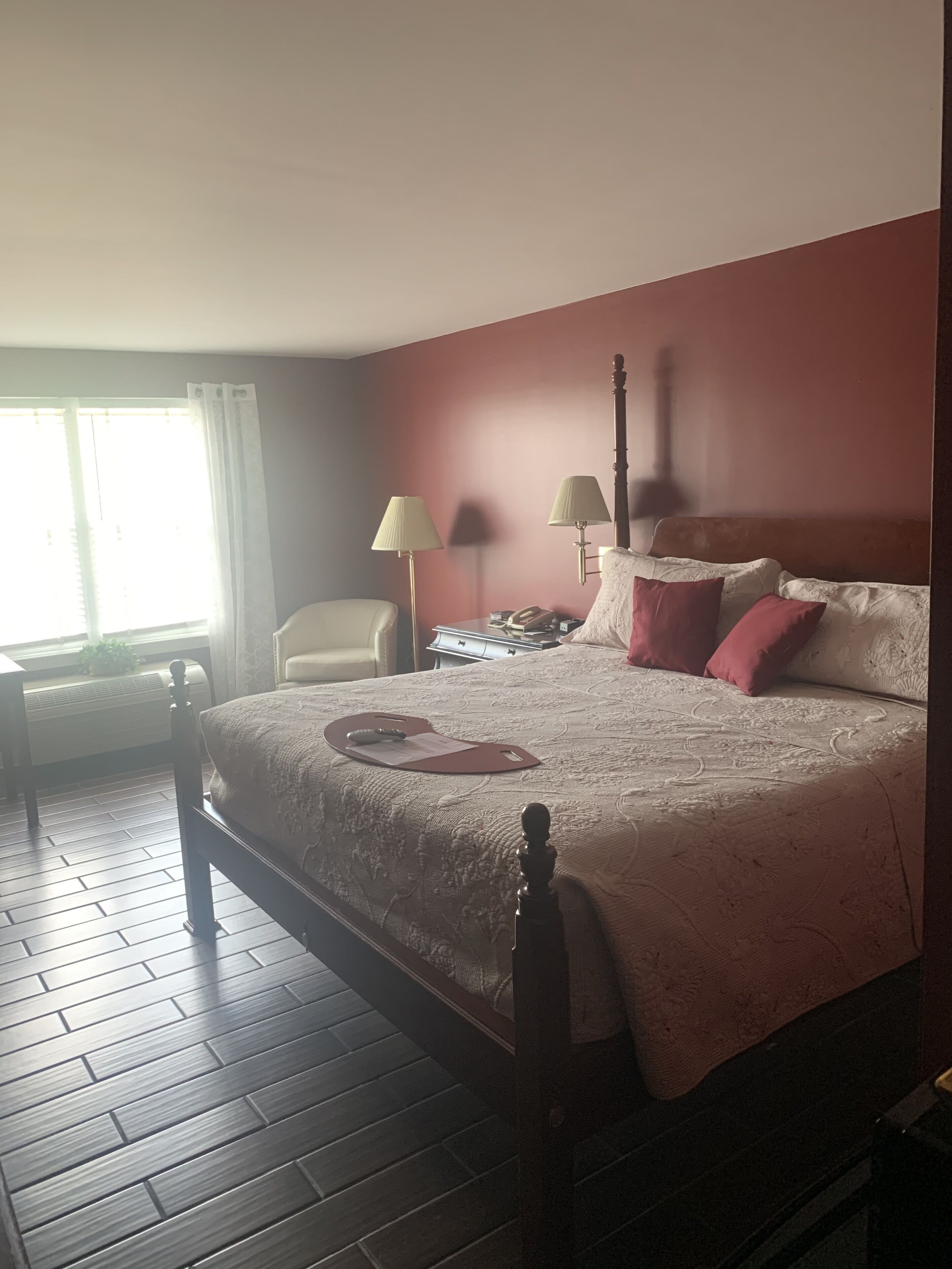 A neatly arranged bedroom with a bed, bedside lamps, a chair, and a desk.