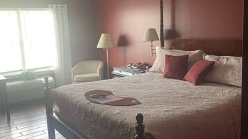 A neatly arranged bedroom with a bed, bedside lamps, a chair, and a desk.