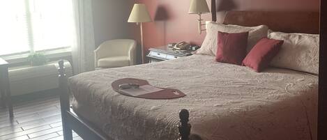 A neatly arranged bedroom with a bed, bedside lamps, a chair, and a desk.
