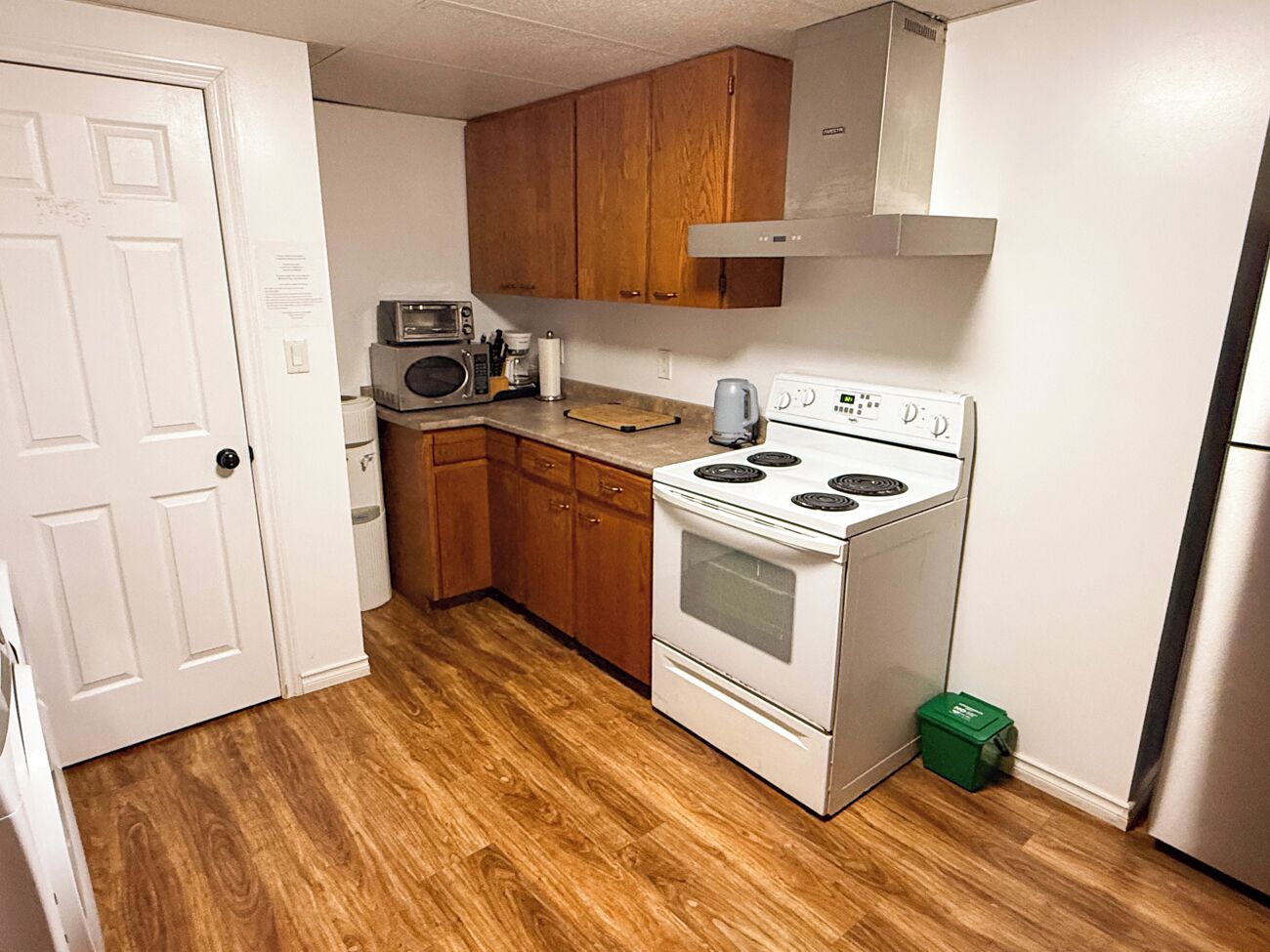 Una cocina compacta con armarios de madera, microondas, estufa y refrigerador.