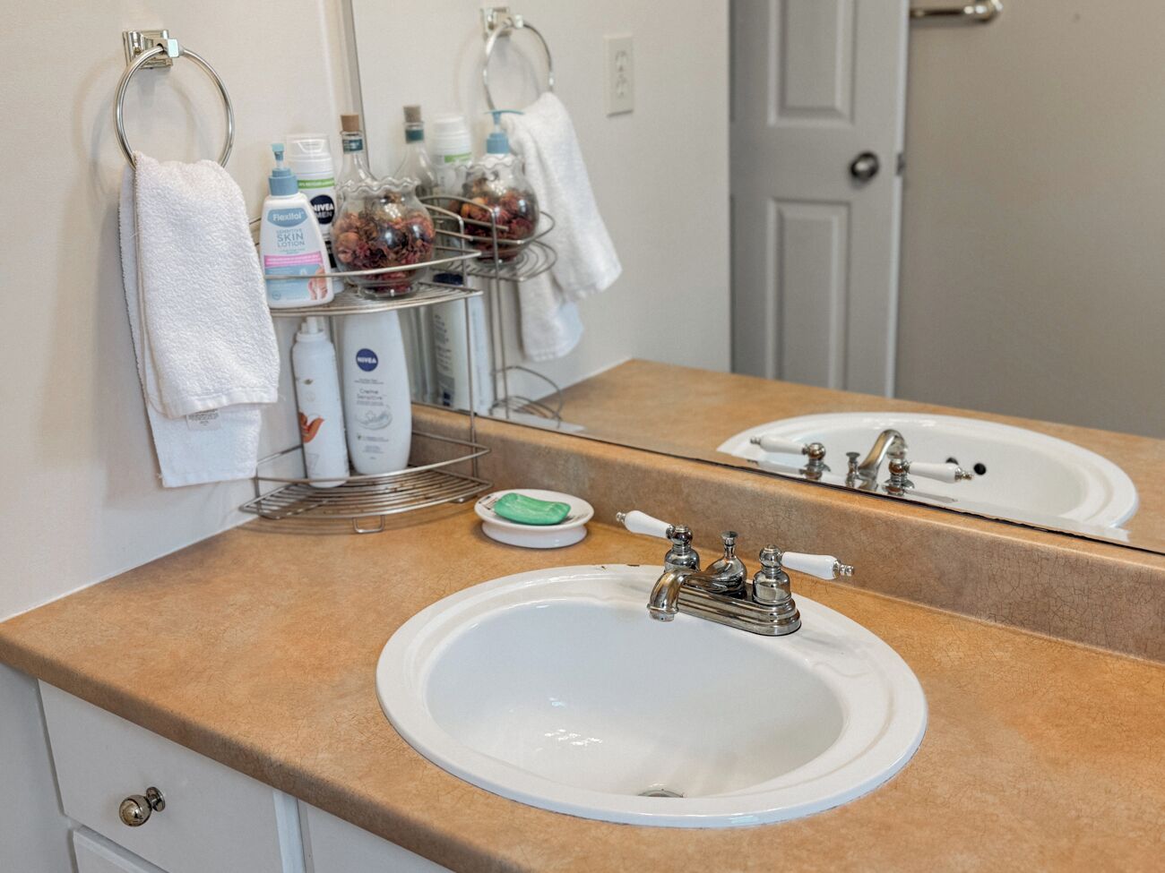 A bathroom with two sinks, a mirror, and toiletries on a shelf.
